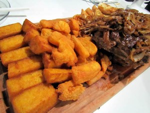 Chuleta: bifes de chuleta aceboladas, polenta frita, aipim frito e pão na chapa